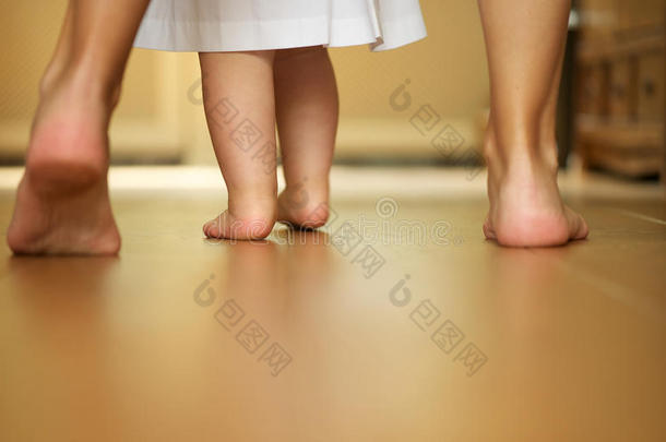 母亲教婴儿在室内行走的画像