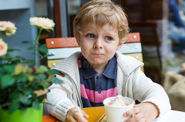 可爱的小男孩在咖啡馆吃冰冻酸奶冰淇淋