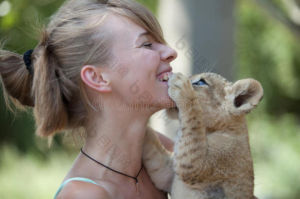 小狮子咬幼兽的女孩在玩耍