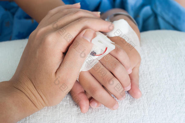 在医院用生理盐水静脉（iv）握住病人男孩的手，表示母亲的<strong>关爱</strong>。