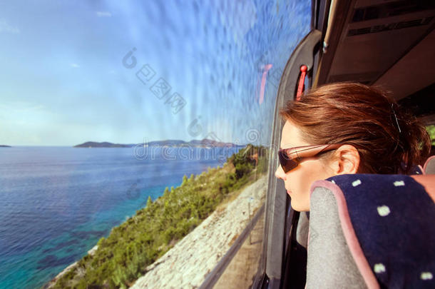 公共汽车上的一位妇女从窗外眺望着海景