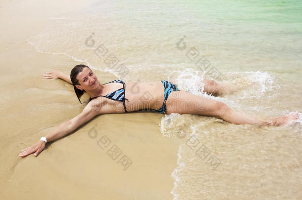 穿着比基尼晒得黝黑的女孩在海滩上的海浪中尽情<strong>挥洒</strong>