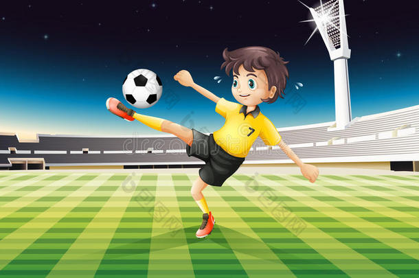 一个穿黄色制服的男孩在球场上踢足球