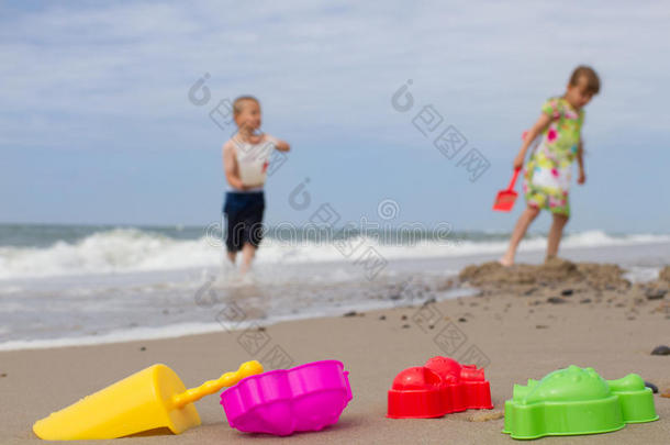 两个孩子和沙滩上五颜六色的塑料玩具