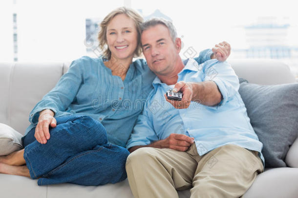 一对幸福的夫妇抱在一<strong>起坐</strong>在沙发上看电视