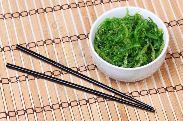 竹席上的陶瓷碗里有芝麻和筷子的海藻。丘卡沙拉。