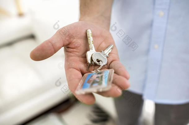 一个男人手里拿着房子的钥匙，在室内。