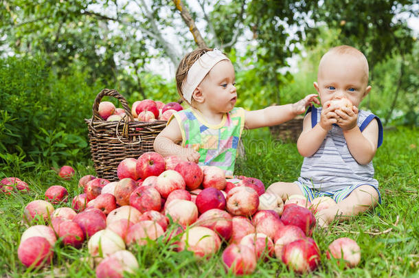 一个小女孩和一个男孩拿着一篮红苹果