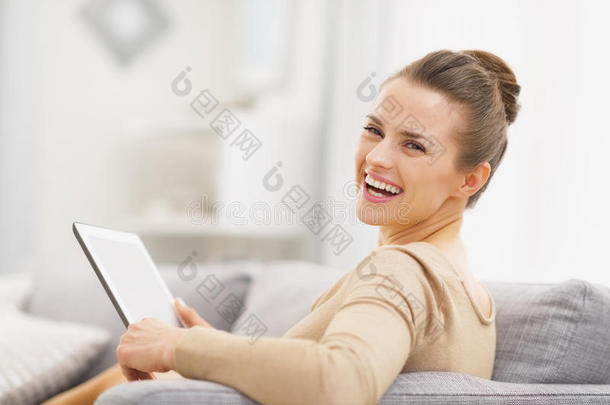 <strong>坐在沙发上</strong>拿着平板电脑微笑的年轻<strong>女子</strong>