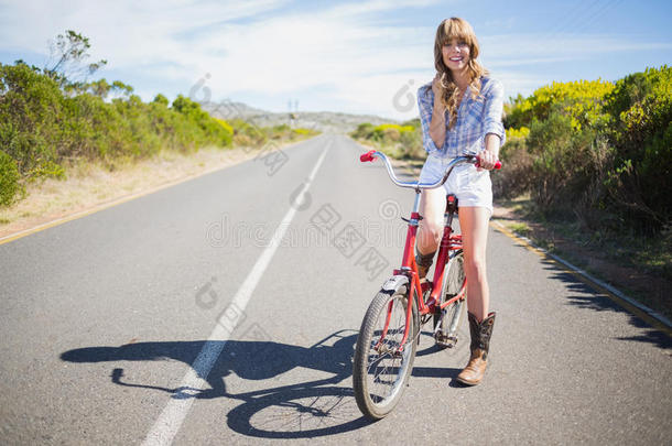 快乐的年轻模特边骑自行车边摆姿势