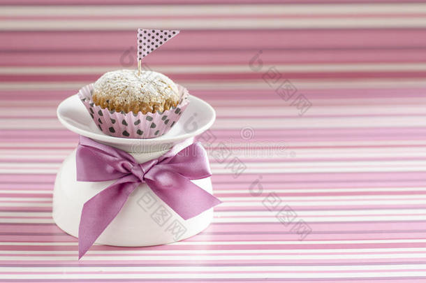白色杯上的南瓜蛋糕，用绸缎蝴蝶结装饰