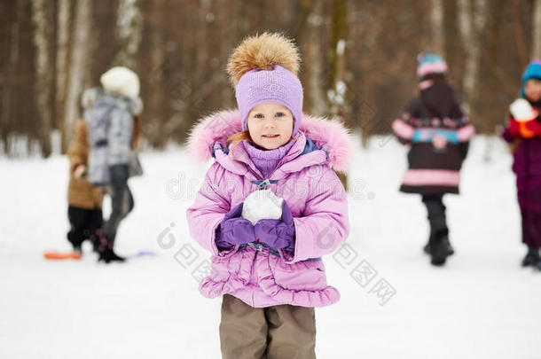 冬季公园里穿着粉色夹克、带毛领的小女孩站着