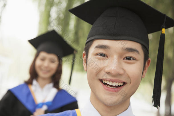 两个年轻的大学毕业生看着镜头，男人在前面