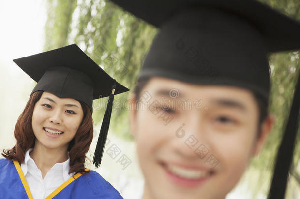 两个年轻的大学毕业生看着镜头，男人在前面
