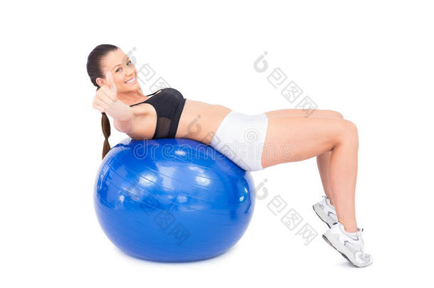 运动型女子用健身球向摄像机伸出大拇指