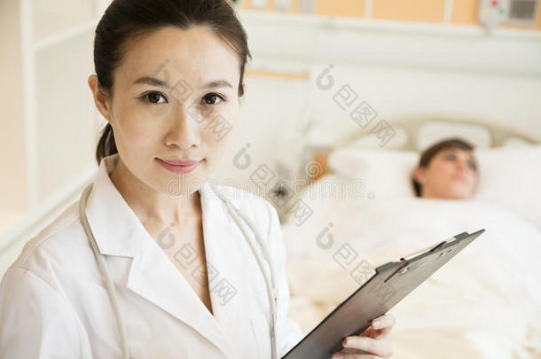 面带微笑的医生拿着病历，病人躺在<strong>病床</strong>上的照片