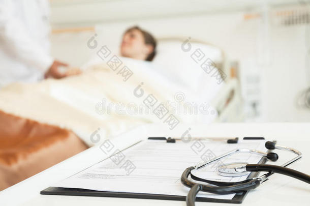 以病人躺在病床上为背景的听诊器和病历特写
