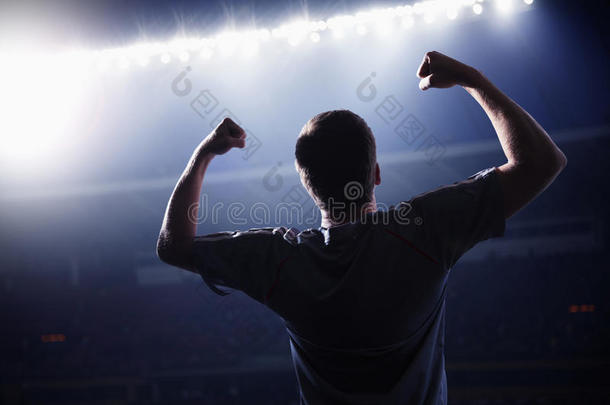 夜间体育场，举臂欢呼的足球运动员