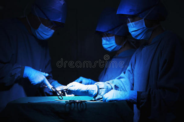 一队外科医生拿着手术器械在手术台上工作