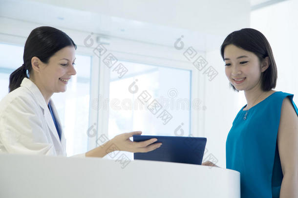 微笑的医生和病人站在医院的柜台旁俯视病历