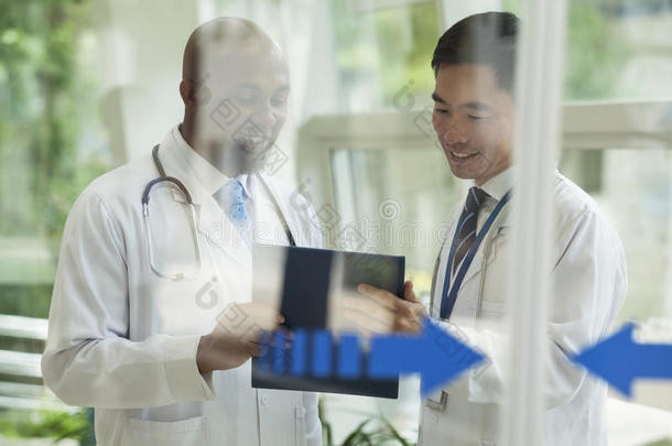 两个医生在玻璃门的另一边查阅病历