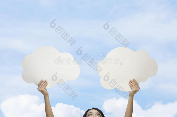 一个年轻的女人拿着两个剪纸云顶着蓝天白云