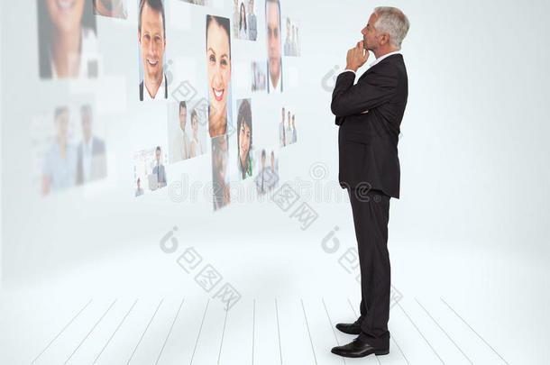 一位体贴的商人看着一堵被个人资料图片覆盖的墙