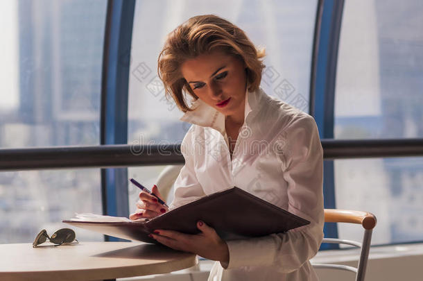 现代商务中心橱窗背景下年轻女商人在文件夹中阅读文件
