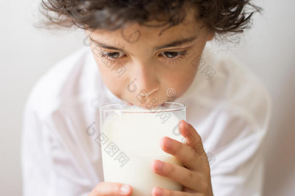 喝一杯牛奶的小男孩。钙的饮食来源。男孩每天都要喝牛奶和钙。