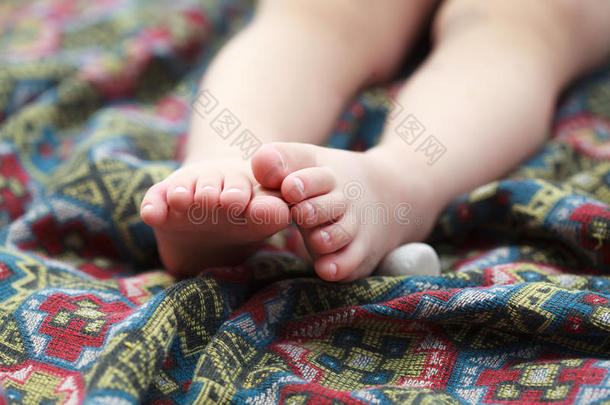 婴儿的脚在一个彩色床罩与几何图案