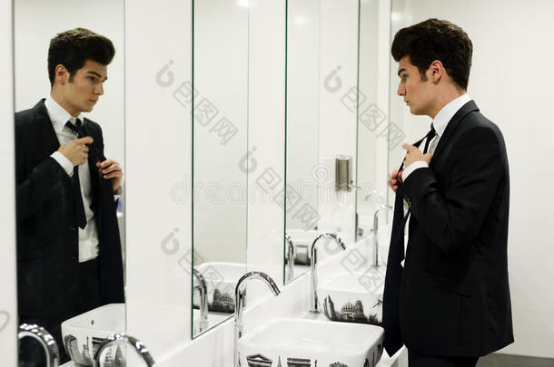 一个男人带着镜子在公共厕所里穿衣