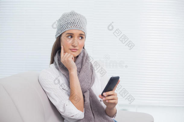 体贴漂亮的黑发女人，戴着冬日帽，手里拿着手机