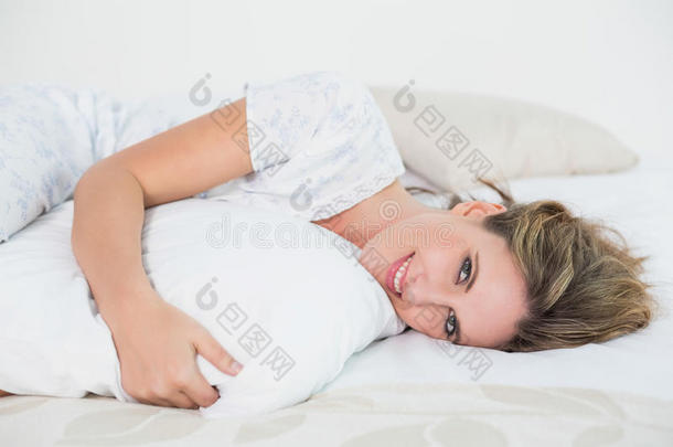微笑的女人躺在床上抱枕