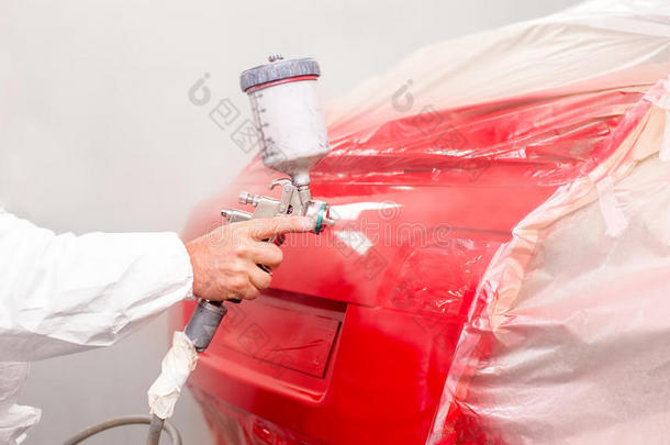 汽车车间汽车油漆工在汽车上喷涂红色油漆