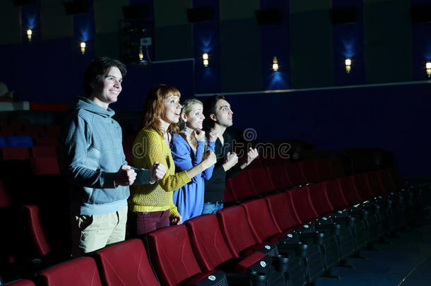 四个快乐<strong>的</strong>朋友站着，看<strong>电影院的</strong>银幕。