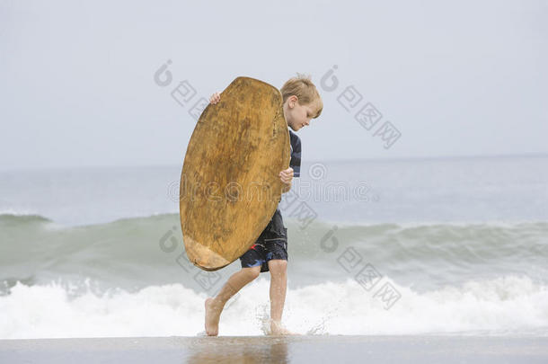 小男孩在海里提着滑板