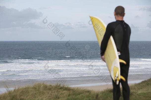 带冲浪板在海滩上看海的冲浪者