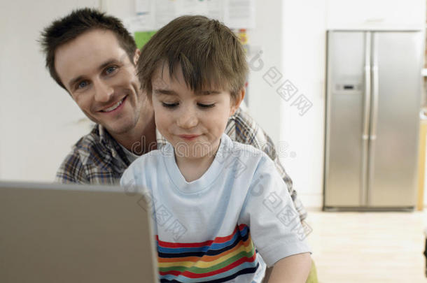 快乐的<strong>父亲和儿子在家里</strong>用笔记本电脑