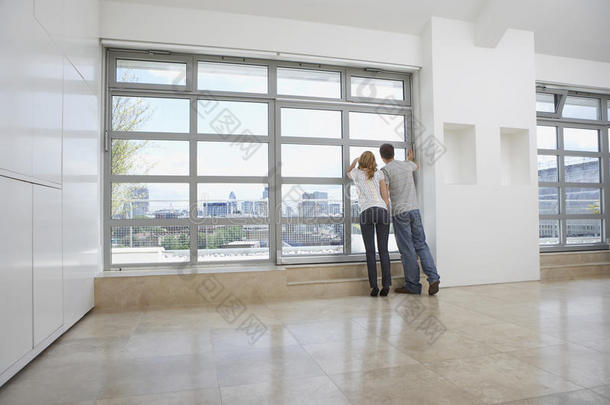 一对夫妇在空荡荡的公寓里望着窗外