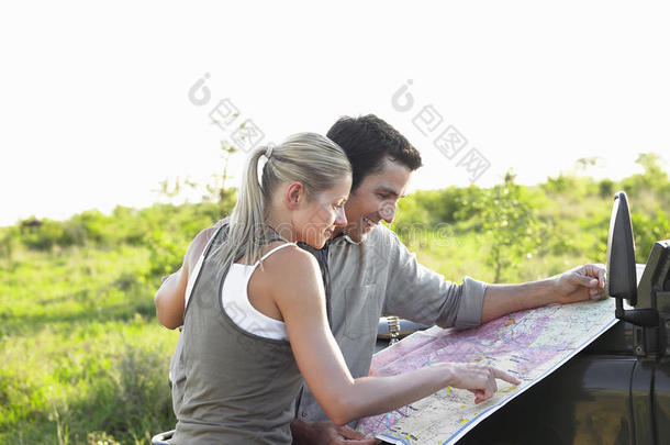一对夫妇在风景区看吉普车引擎盖上的地图