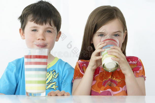 孩子们用五颜六色的玻璃杯喝牛奶