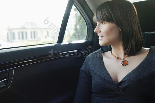 坐在汽车后座的女商人望着窗外