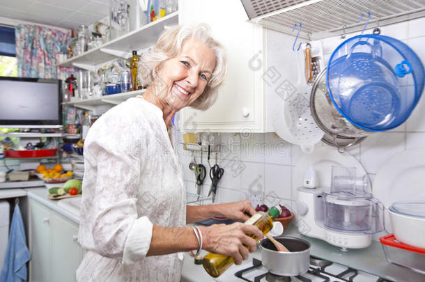 家政厨房老太太往锅里倒橄榄油的画像