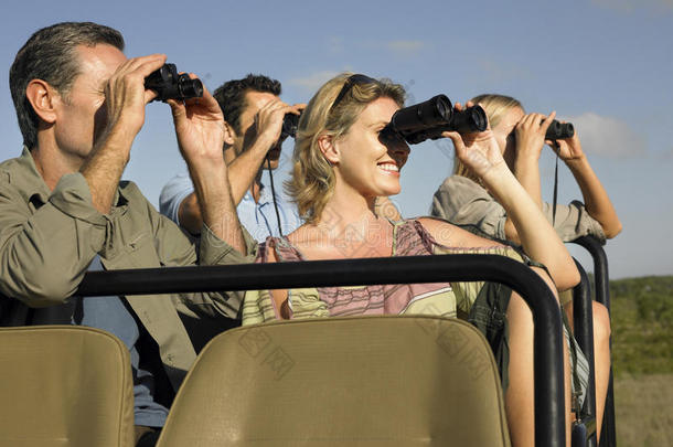 乘坐吉普车的游客透过望远镜观看