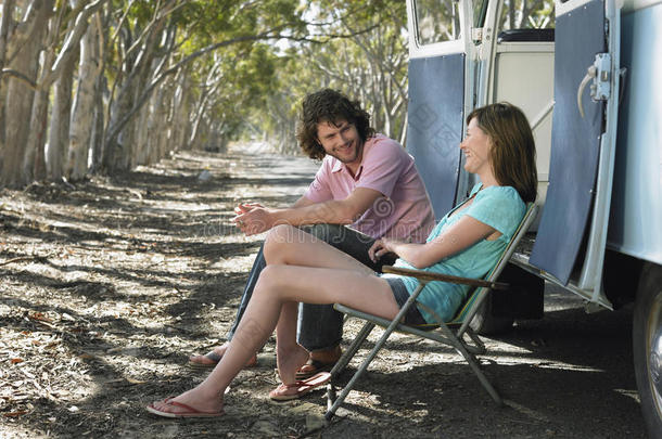一对夫妇坐在露营车旁的躺椅上