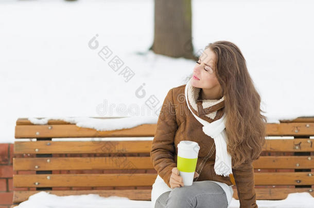 快乐的年轻女子拿着一杯热饮料享受冬天