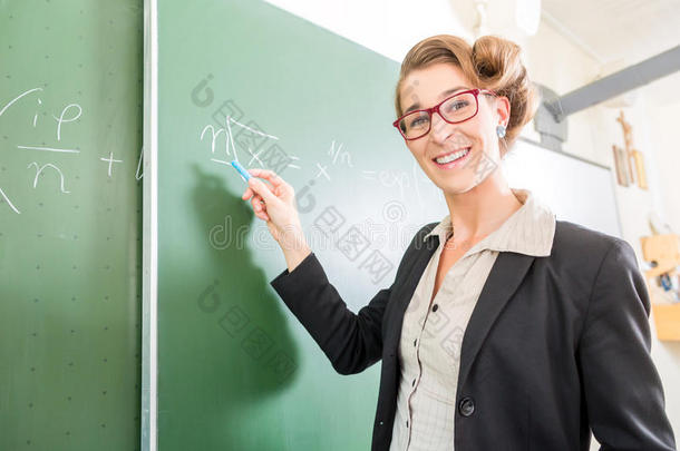 老师在黑板上的教室前用粉笔写字