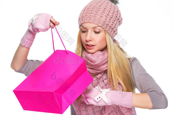 好奇的女孩穿着冬天的衣服，看着购物袋