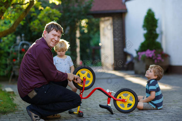 两个可爱的男孩和父亲在户外修理<strong>自行车轮子</strong>的肖像。
