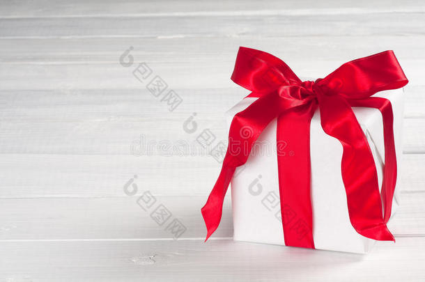 白色纸包装的圣诞礼物，灰色和白色背景板上有红色缎带，留有文字空间